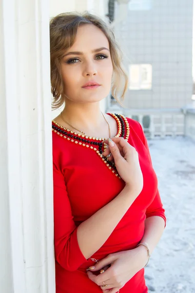 Chica en un vestido rojo de pie contra la pared — Foto de Stock