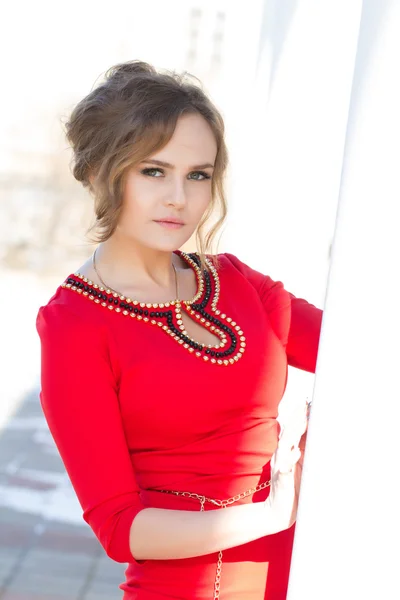 Girl in a red dress standing against the wall — Stock Photo, Image