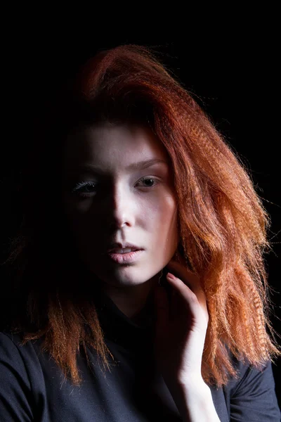 Tjej med rött hår på en svart bakgrund — Stockfoto