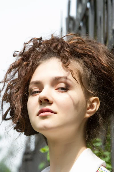 A girl stands at the metal fence in the park — Stock Photo, Image