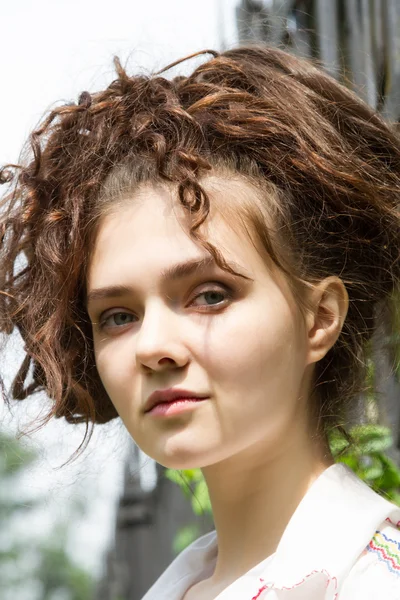 A girl stands at the metal fence in the park — Stock Photo, Image