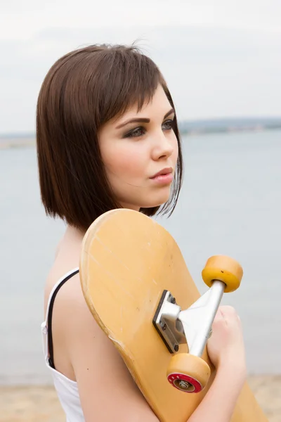 Una ragazza che tiene uno skateboard — Foto Stock