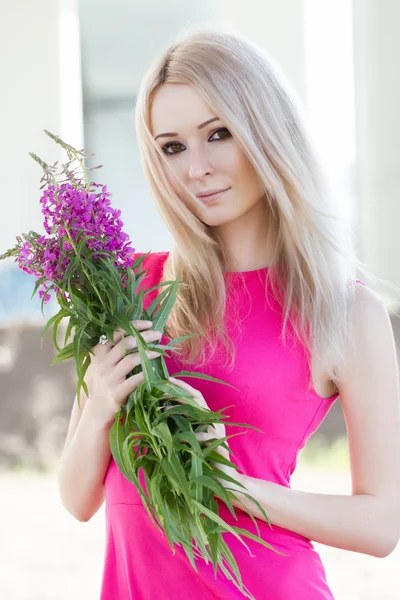 La blonde en robe rose recueille un bouquet de fleurs sauvages — Photo