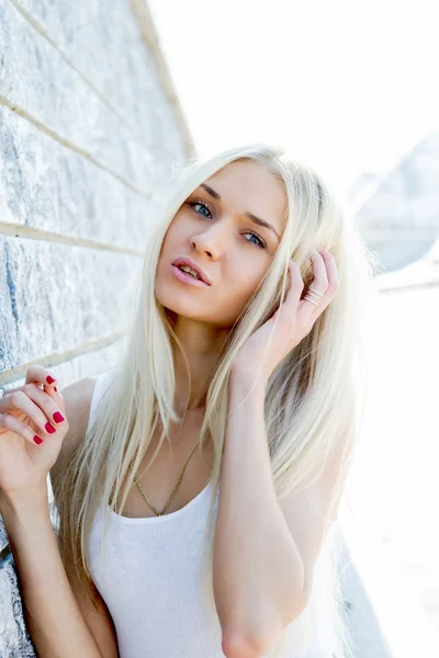 Blondes Mädchen im T-Shirt lehnt an Granitwand — Stockfoto