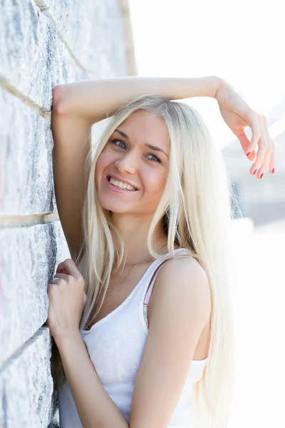 Blondes Mädchen im T-Shirt lehnt an Granitwand — Stockfoto