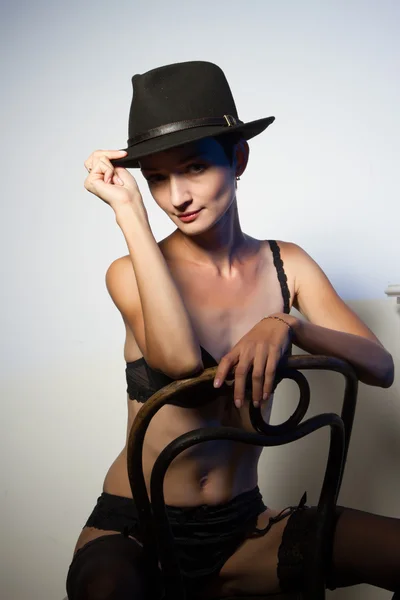 Fille en lingerie et chapeau assis sur une chaise — Photo