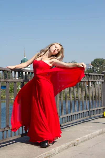 The girl on the waterfront in a red evening dress — Stock Photo, Image