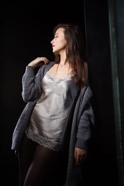 Chica de pie en la ventana en una habitación oscura — Foto de Stock