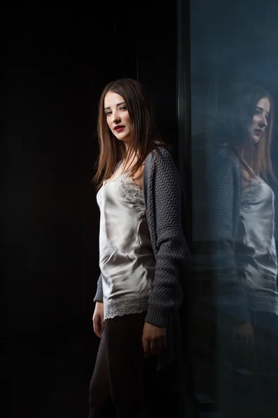 Девушка, стоящая у окна в темной комнате — стоковое фото