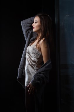 Karanlık bir odada bir pencere yakınında duran kız