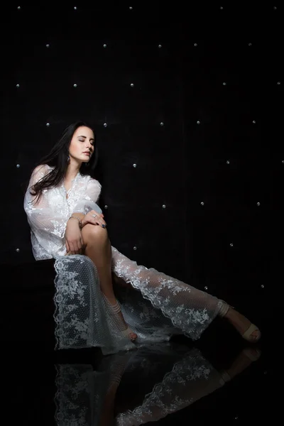 Chica joven en un vestido blanco en una habitación oscura — Foto de Stock