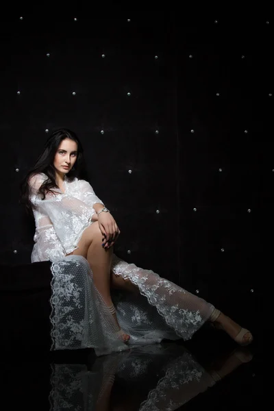 Young girl in a white dressing gown in a dark room — Stock Photo, Image