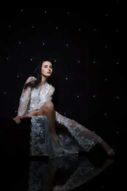 Genç kız bir sabahlık ve karanlık bir arka plan üzerinde iç çamaşırı