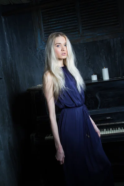 Dívka ve večerních šatech na pozadí piano — Stock fotografie