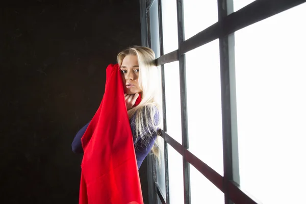 Penceredeki kırmızı bir eşarp ile genç sarışın — Stok fotoğraf