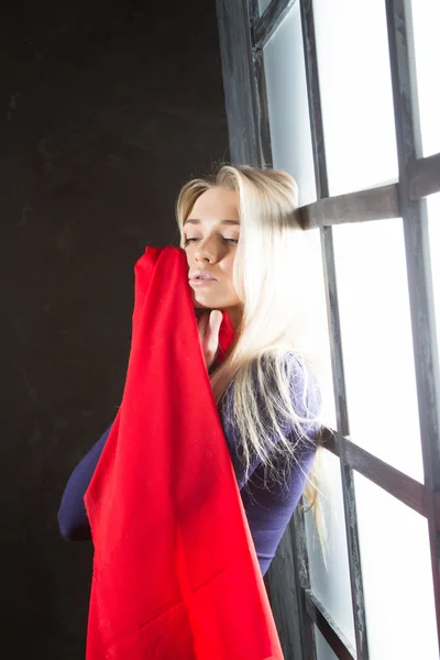Jovem loira com um lenço vermelho na janela — Fotografia de Stock