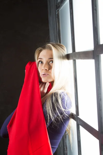 Jovem loira com um lenço vermelho na janela — Fotografia de Stock