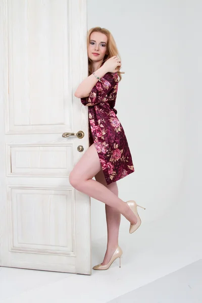 Jong meisje in een korte gewaad kleur gluren uit achter de deur — Stockfoto