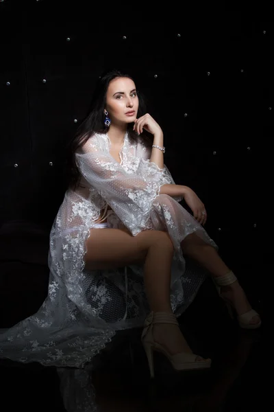 Portrait of a young woman in a lace peignoir on a black background — Stock Photo, Image