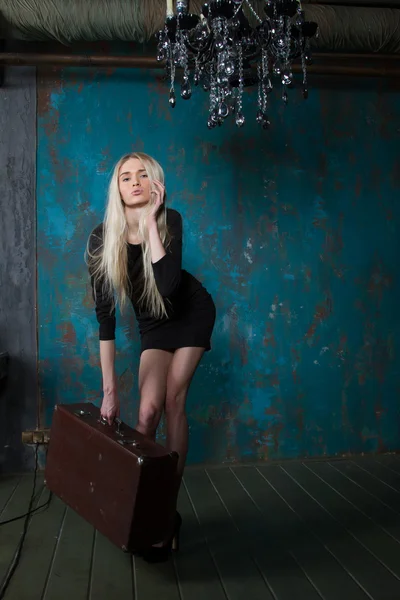 Thin, fragile blonde with a huge suitcase in an old room — Stock Photo, Image