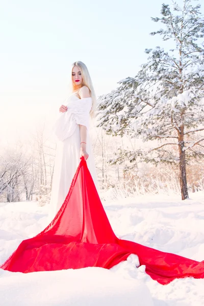 Jovem em um vestido branco em um fundo de floresta coberta de neve — Fotografia de Stock