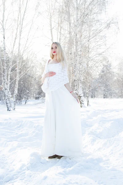 Ung flicka i en vit klänning på en bakgrund av snöklädda skogen — Stockfoto