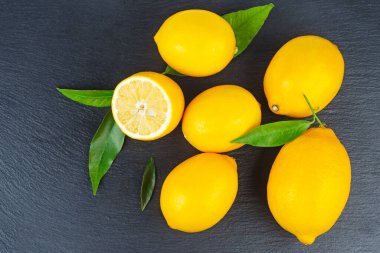 Yeşil yapraklı limon yığını siyah bir levhada