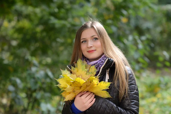 Jeune femme aux feuilles d'automne à la main Photo De Stock