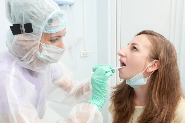 Doktor olası bir koronavirüs enfeksiyonu için hastadan boğaz ve genizden örnek alıyor. Koronavirüs analizi. Covid 19