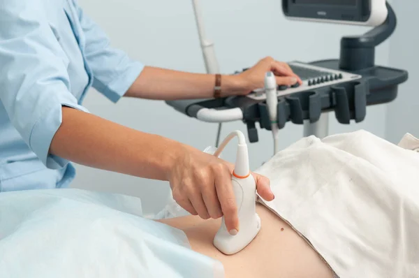 Doktor kızın iç organlarını ultrason ile muayene ediyor. Doktor sensörü arka taraftan çalıştırıyor.
