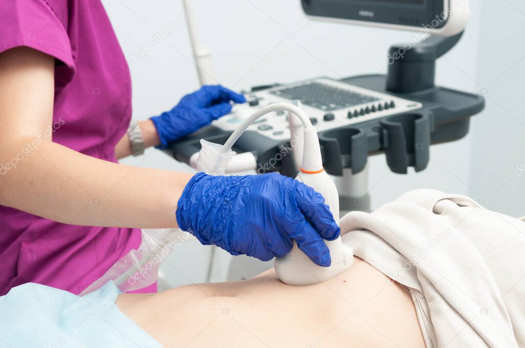 The doctor makes an ultrasound diagnosis of young girl abdomen. Ultrasound investigation.