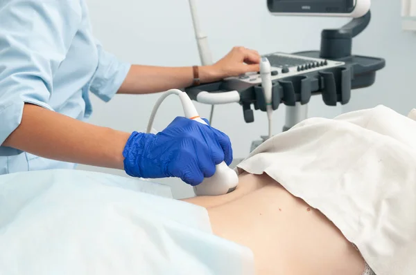 Böbreklerin ultrason araştırması. Doktor kızın sırtındaki ultrason sensörünü çalıştırıyor..