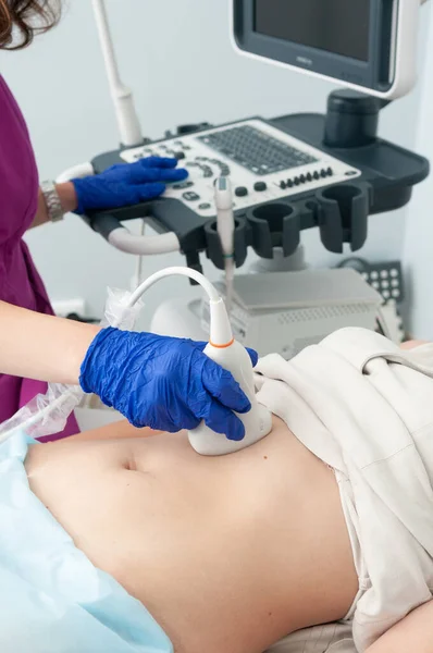 Genç bir kızın karnının ultrasonu. Doktor karın bölgesinde ultrason muayenesi yapıyor..