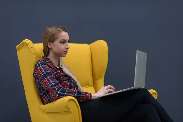 Nystartat företag, Kvinna arbetar på bärbar dator och sitter på gul — Stockfoto