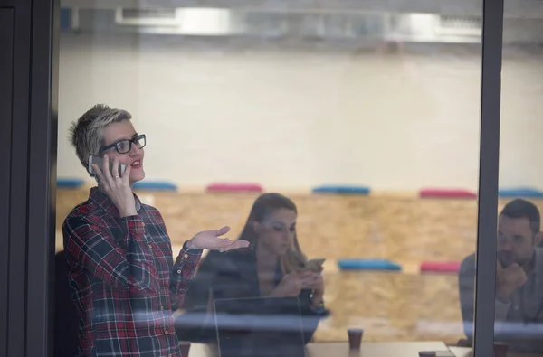 Zakenvrouw op kantoor spreken door telefoon team op de bijeenkomst in b — Stockfoto