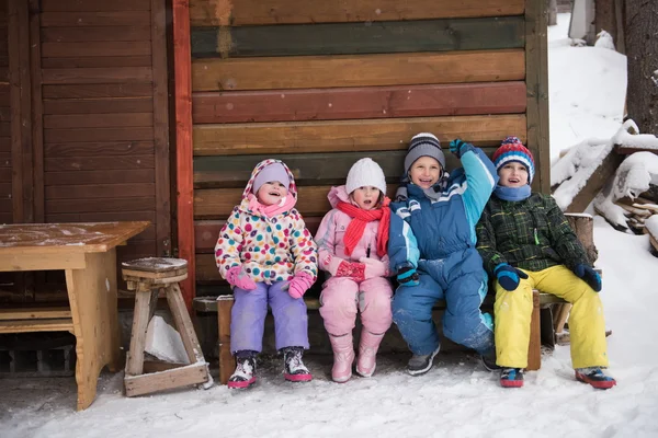 Маленькая детская группа, сидящая вместе перед деревянными кабинками — стоковое фото