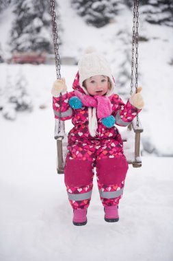 karlı kış günü küçük kıza parkta salıncak