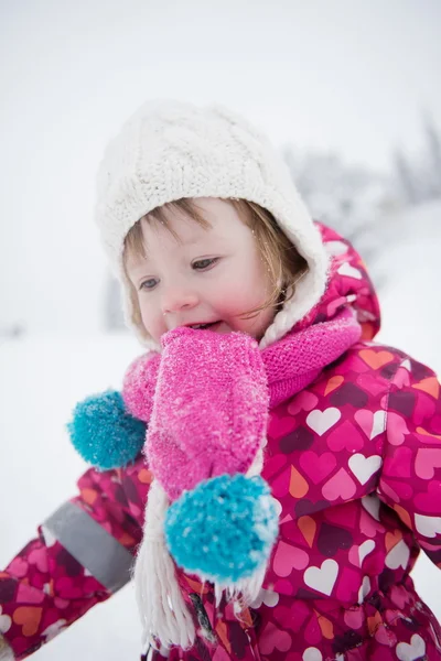 Malá holčička se bavit na zasněžené zimní den — Stock fotografie