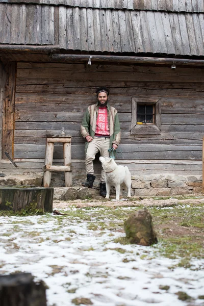 Hipster con perro delante de casa de madera — Foto de Stock