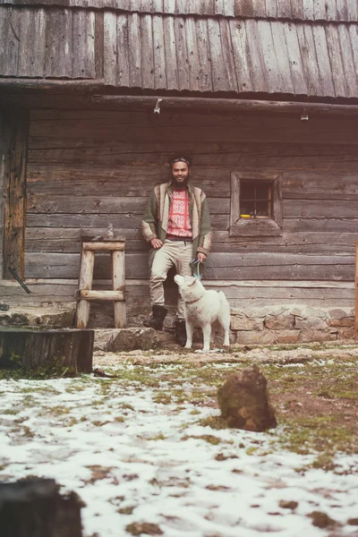 Хіпстер з собакою перед дерев'яним будинком — стокове фото
