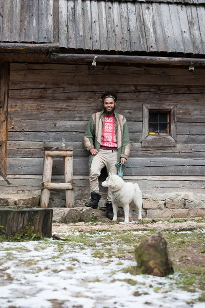 Hipster con perro delante de casa de madera — Foto de Stock