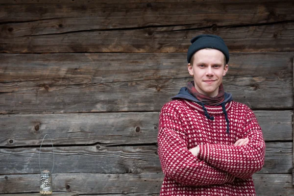 Young hipster in front of wooden house — Stock Photo, Image