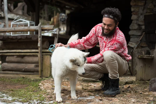 Хипстер с собакой перед деревянным домом — стоковое фото