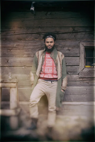 Portret van jonge hipster voor houten huis — Stockfoto