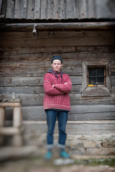 Joven hipster en frente de casa de madera — Foto de Stock