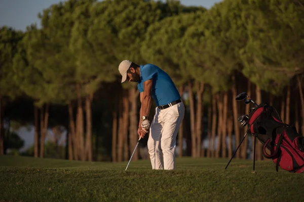Golfspelare slår en sand bunker skott på sunset — Stockfoto