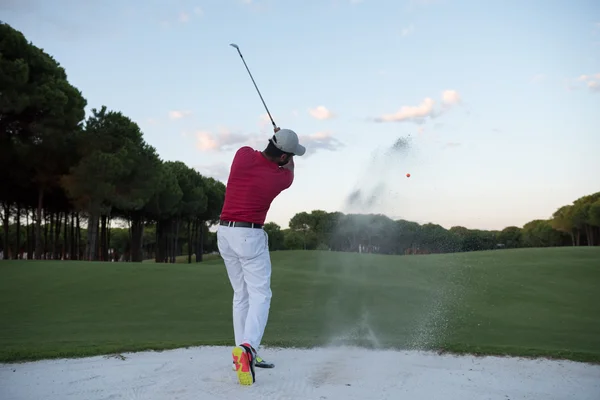 Golfer raken van een zand bunker shot op zonsondergang — Stockfoto
