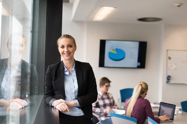 Retrato de la joven mujer de negocios en la oficina con el equipo en la reunión — Foto de Stock