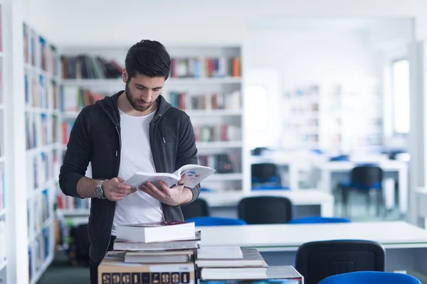 Étudiant tout en lisant le livre dans la bibliothèque scolaire — Photo