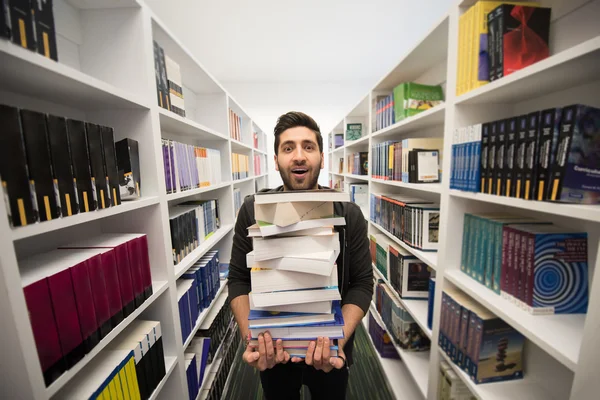 Studente che tiene molti libri nella biblioteca della scuola — Foto Stock